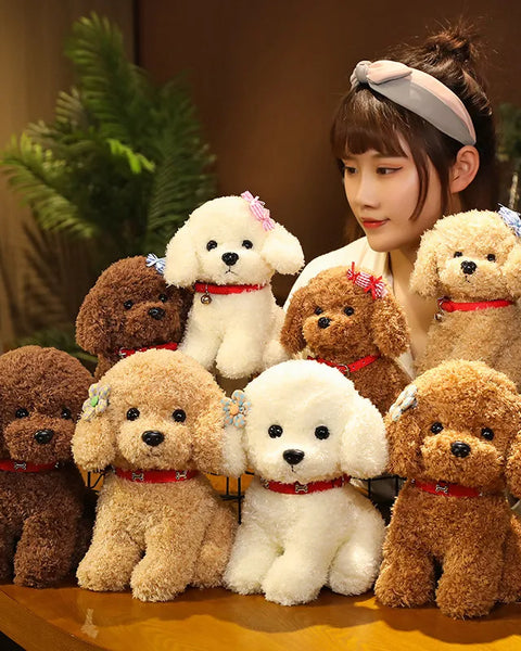 Woman sitting behind a collection of small, fluffy teddy dog plush toys in various shades of brown and white, each wearing a red collar and some decorated with bows.